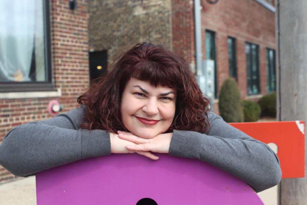 Rev. Denise Cawley wearing grey sweater on purple letter D