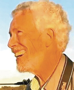 profile of older man with white hair and camera strap around his neck