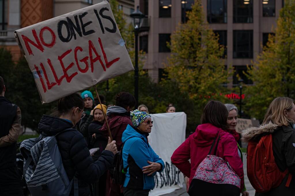A group of diverse adults protesting immigration policies with signs outdoors.